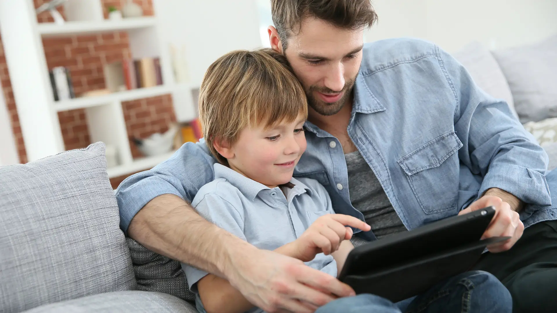 Dad using a tablet with his son because he is doing the parental controls