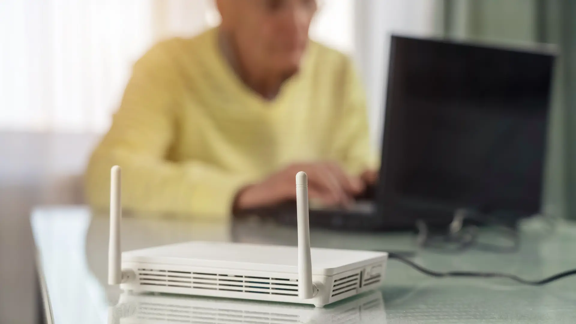 Old men using her laptop because he has hired a Gigaclear wifi router