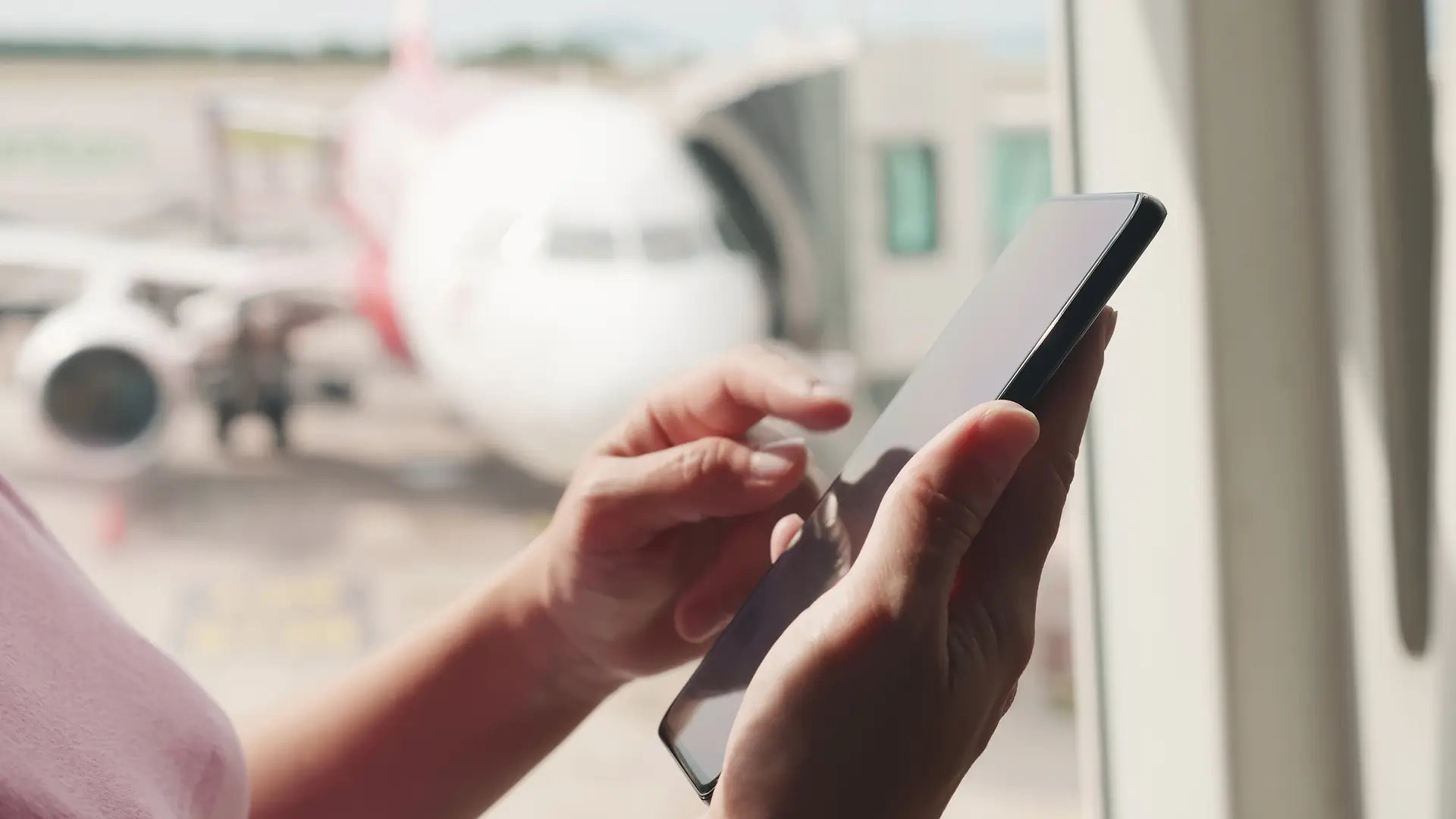 Hand holding a mobile in front of a plane representing Smarty roaming