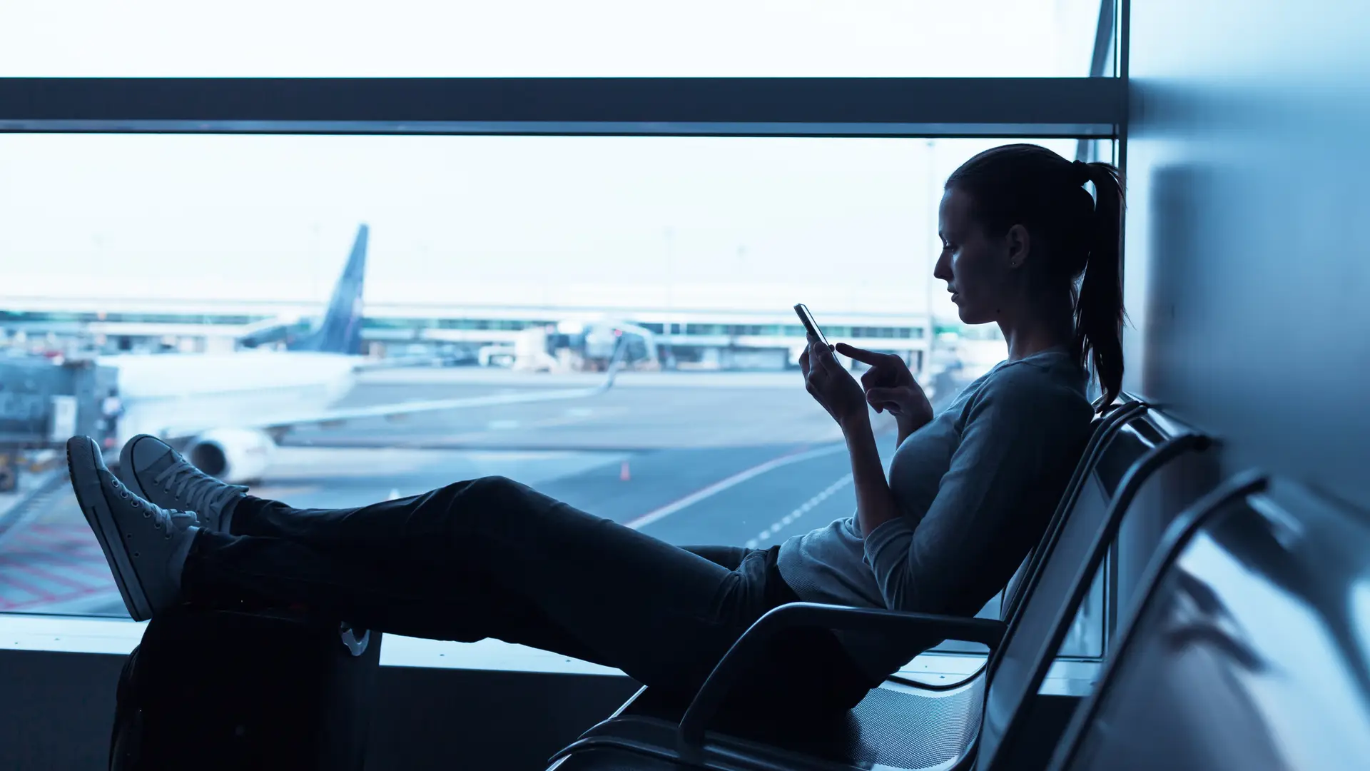 Young girl at the airport cheking Talkmobile roaming plans at her phone