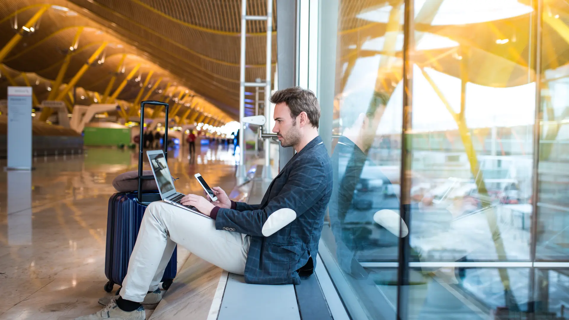 Men using his phone at the airport searching Tesco roaming plans