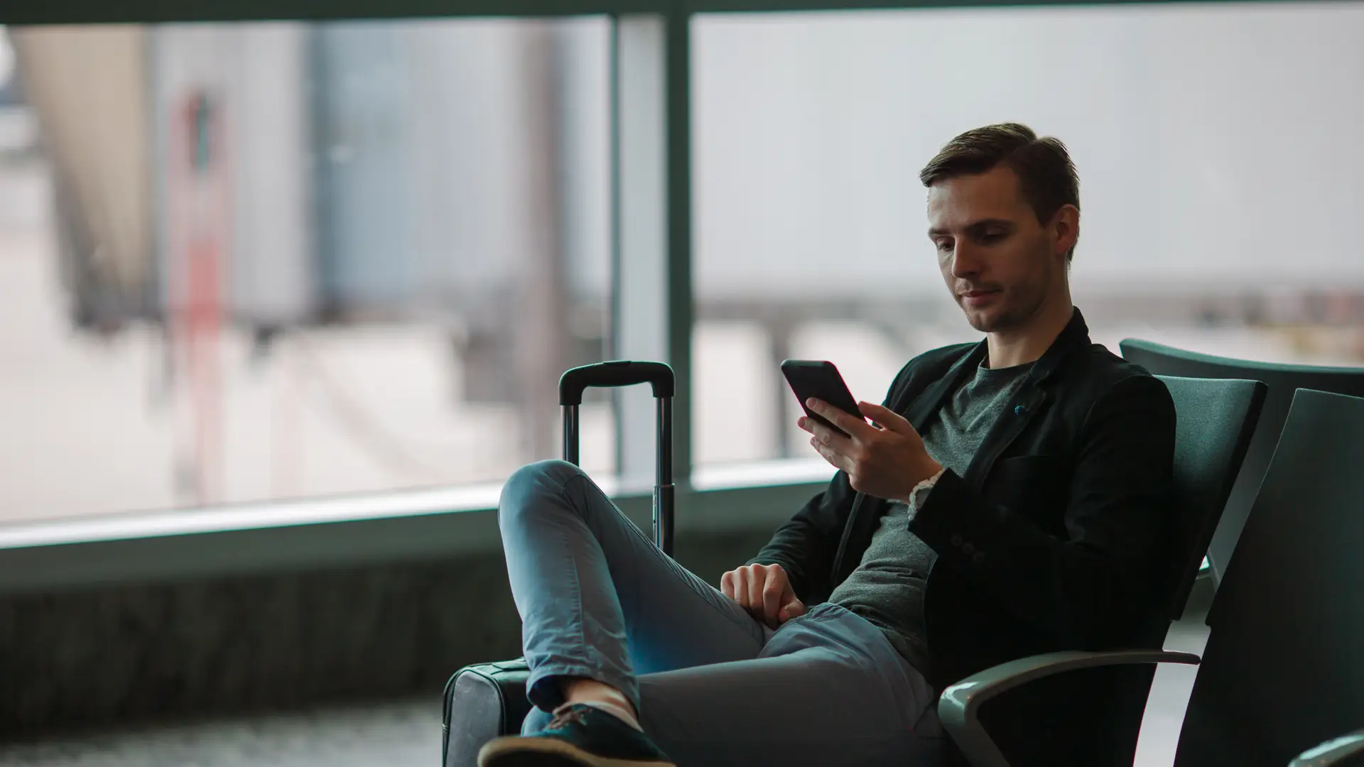 Men at the airport checking on his phone Three roaming plans